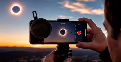 Persona grabando el eclipse solar de 2026 con el móvil y filtro de protección