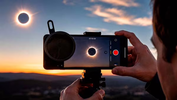 Persona grabando el eclipse solar de 2026 con el móvil y filtro de protección