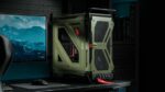 CORSAIR WARTHOG Airflow verde oliva montado en un escritorio gaming con diseño industrial y asas integradas