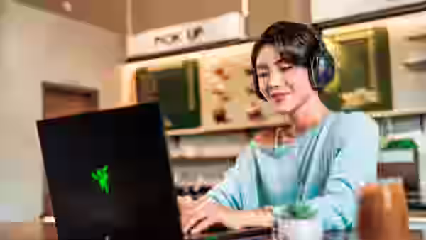 Persona usando los Razer Barracuda V2 Pro con un portátil en una cafetería